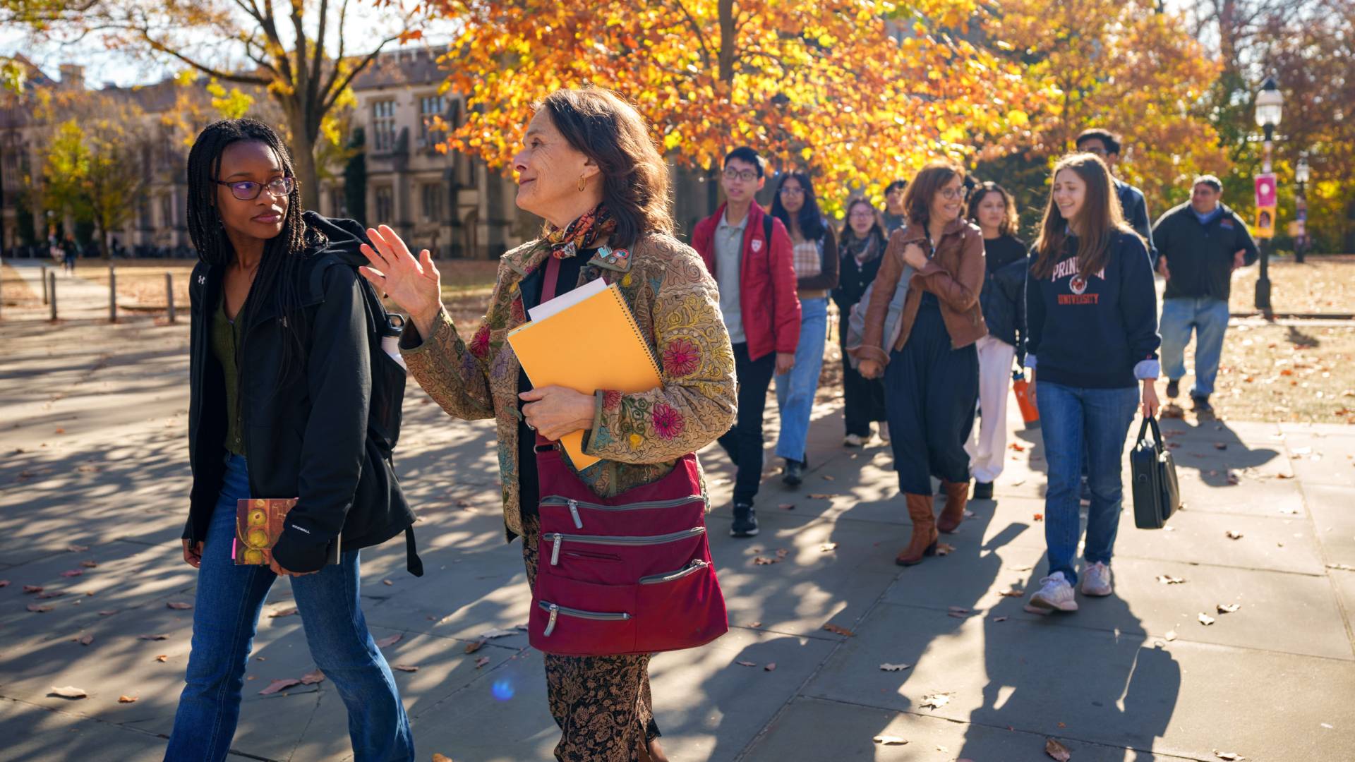 A professor walking across campus with a group of students.