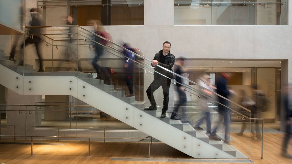 Dalton Conley on stairs with people moving past him