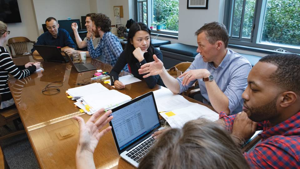 Researchers seated around a table in the Eviction Lab have a discussion