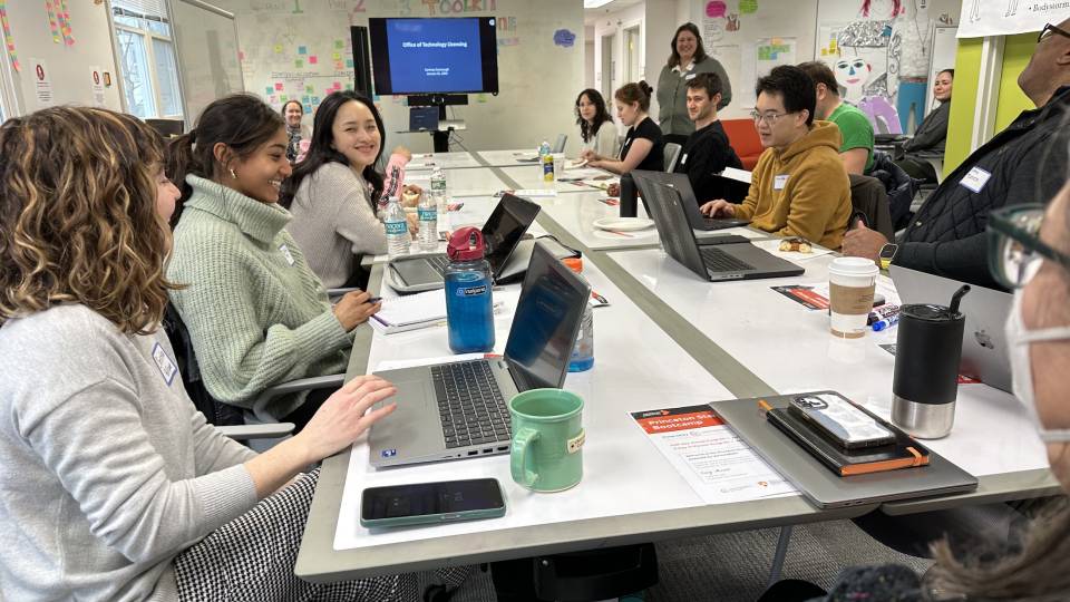 Students smiling and talking around a table during VentureWell boot camp.