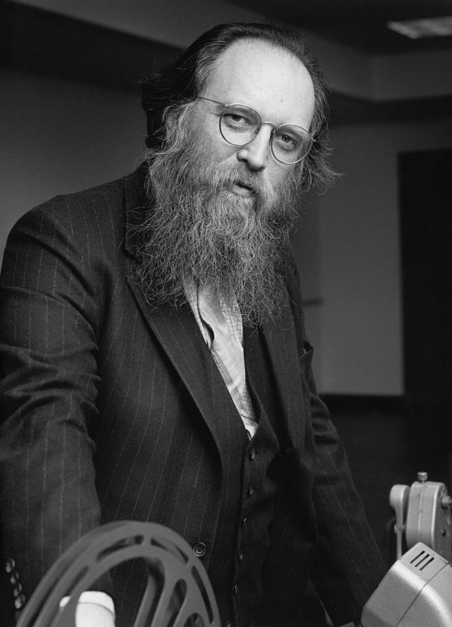 A man with glasses and a very long beard stands in front of a filmstrip projector.