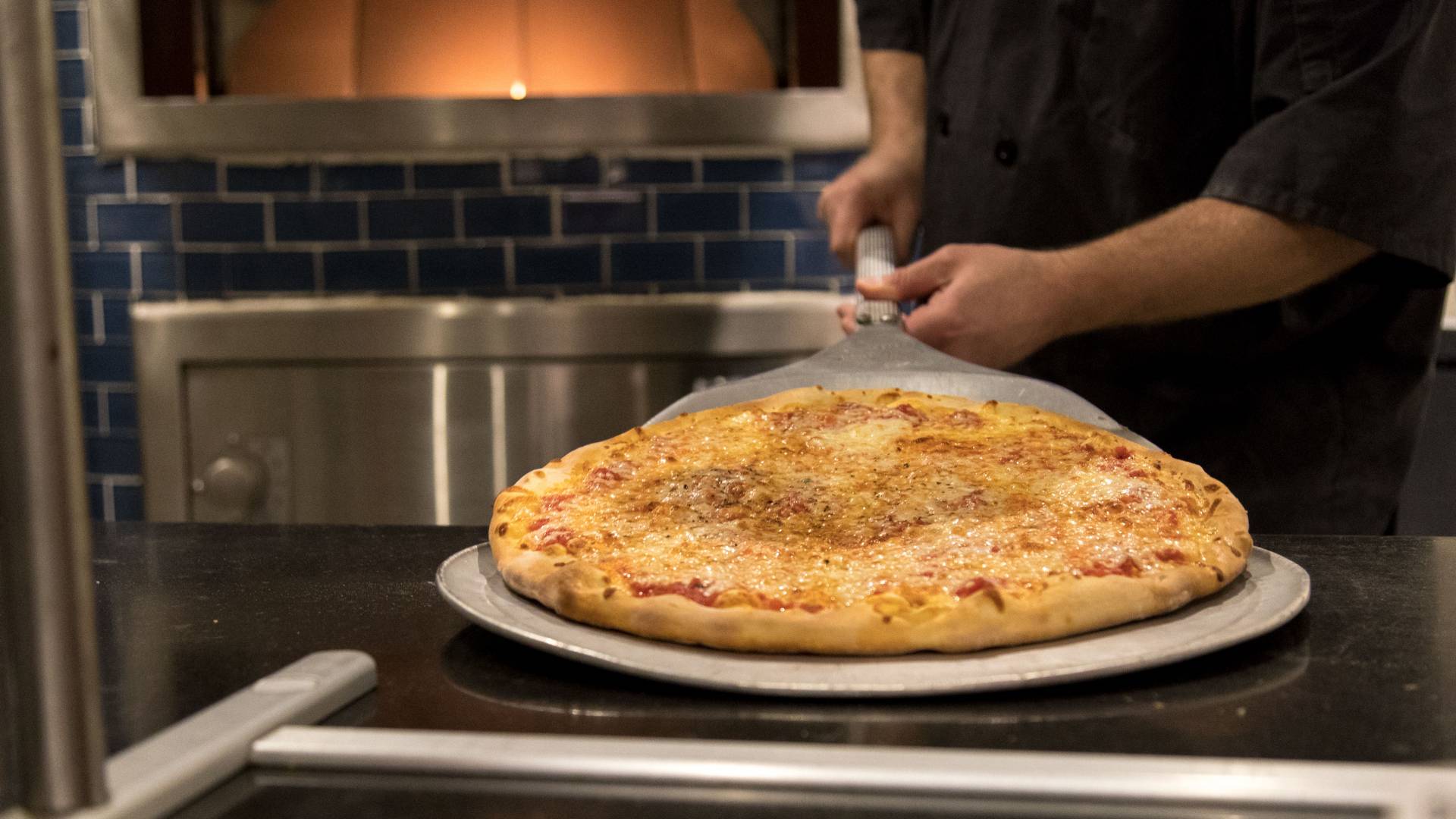 Pizza coming out of oven