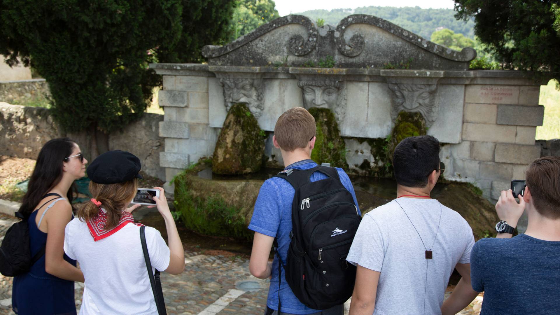 Students looking at fountain with three faced spouts in France