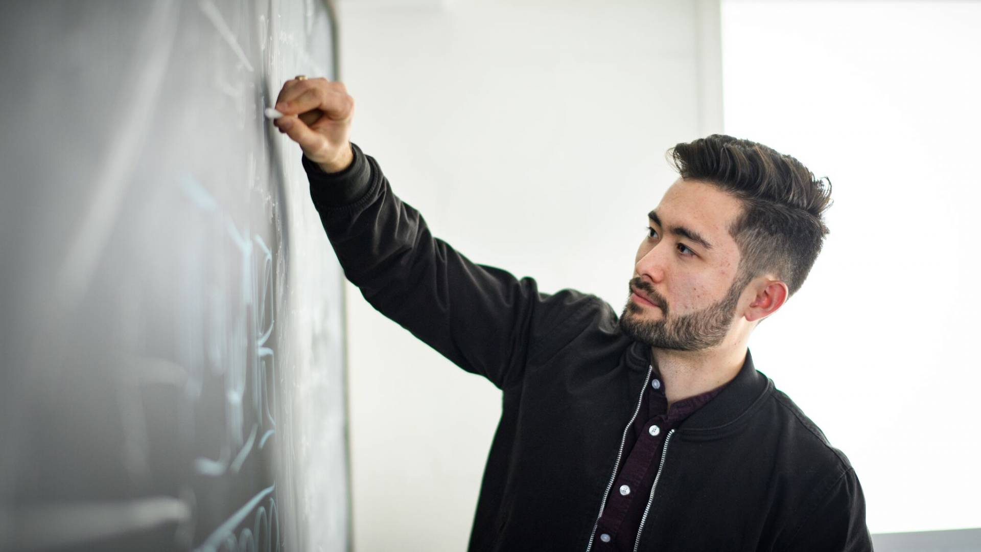 Chris Tokita writing on a blackboard