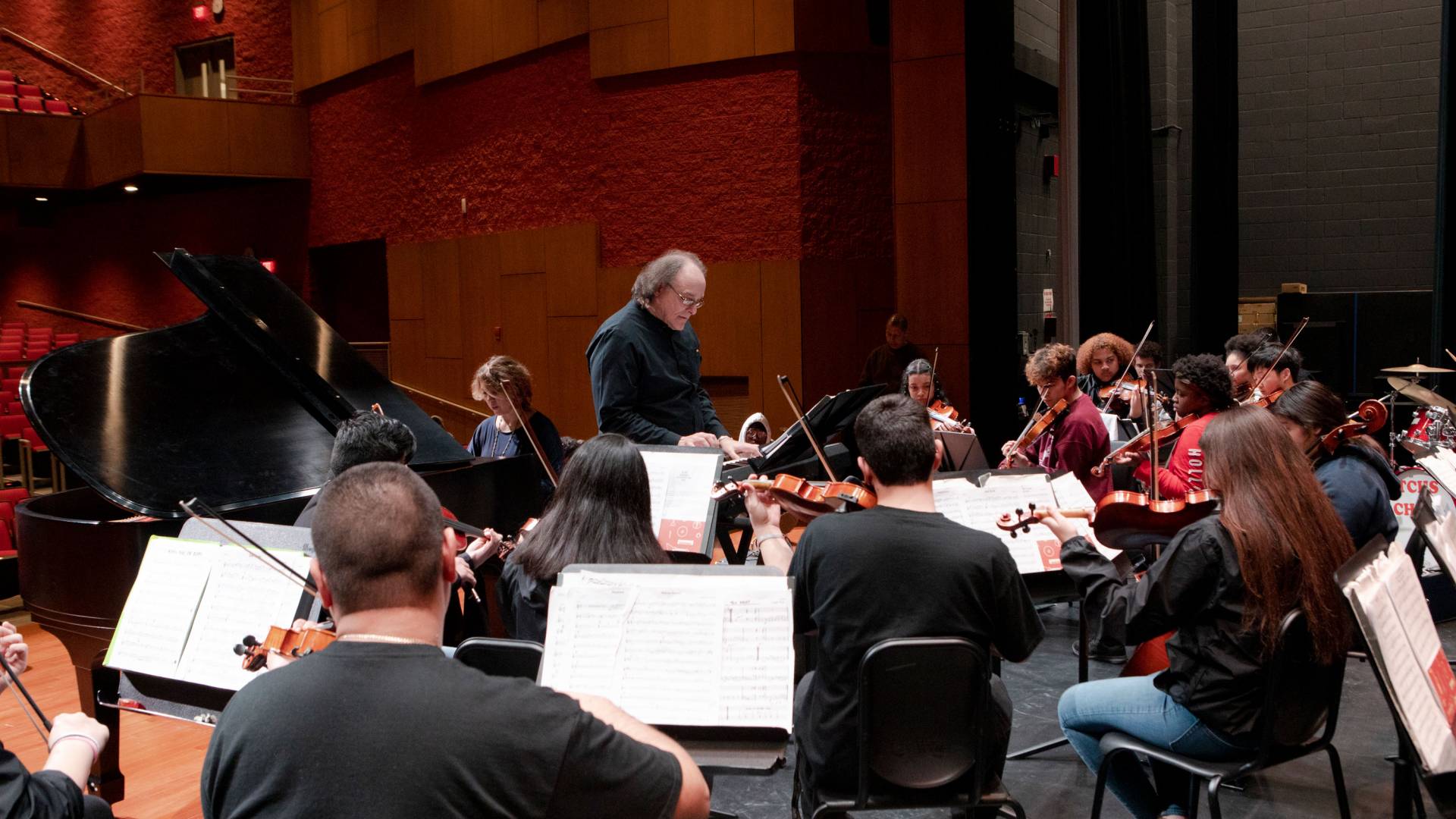 Conductor stands in front of orchestra
