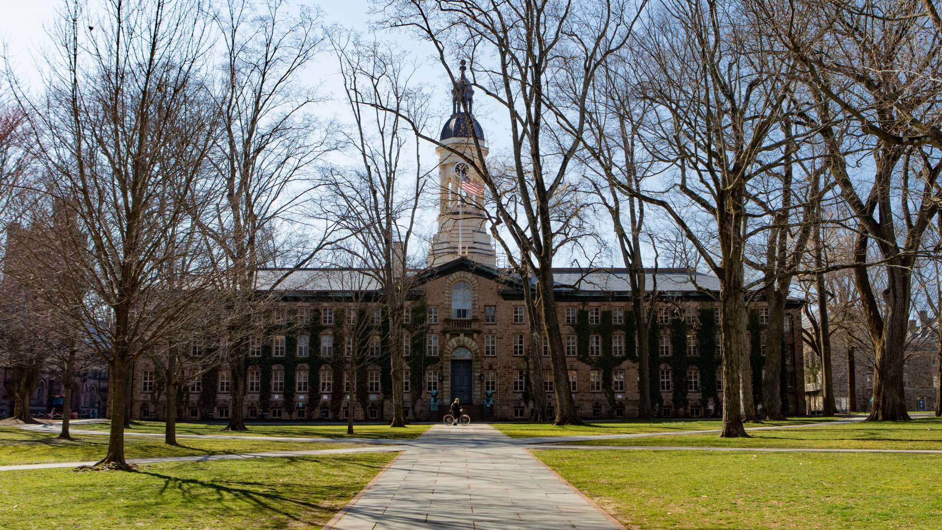 a bicyclist rides by Nassau Hall in spring