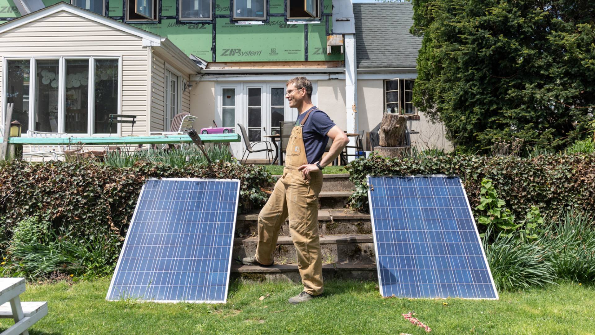 Forrest in front of his house under construction. Flanked by solar panels.