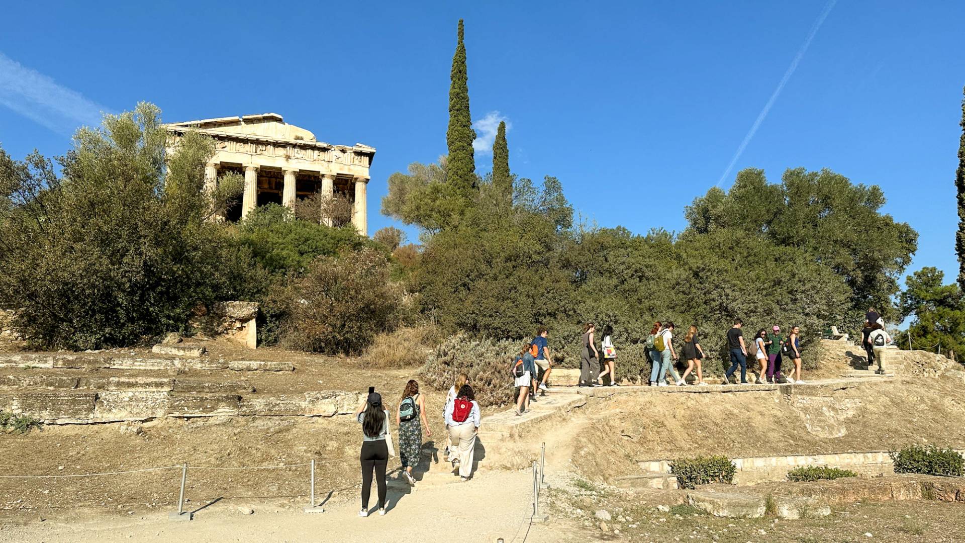 Students walking in a path in Greece. An old structure with pillars in the background.