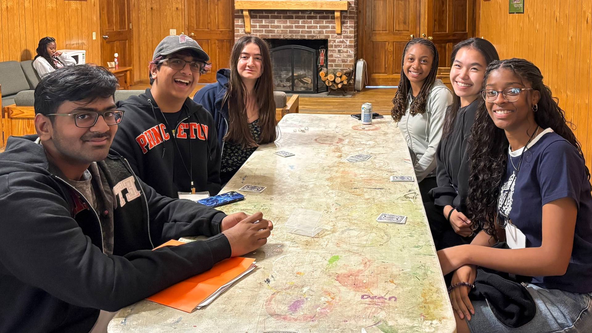 Students sit around a table with playing cards