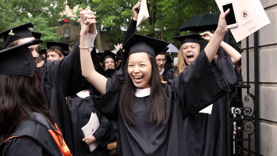 Student walks through gate with arms up cheering