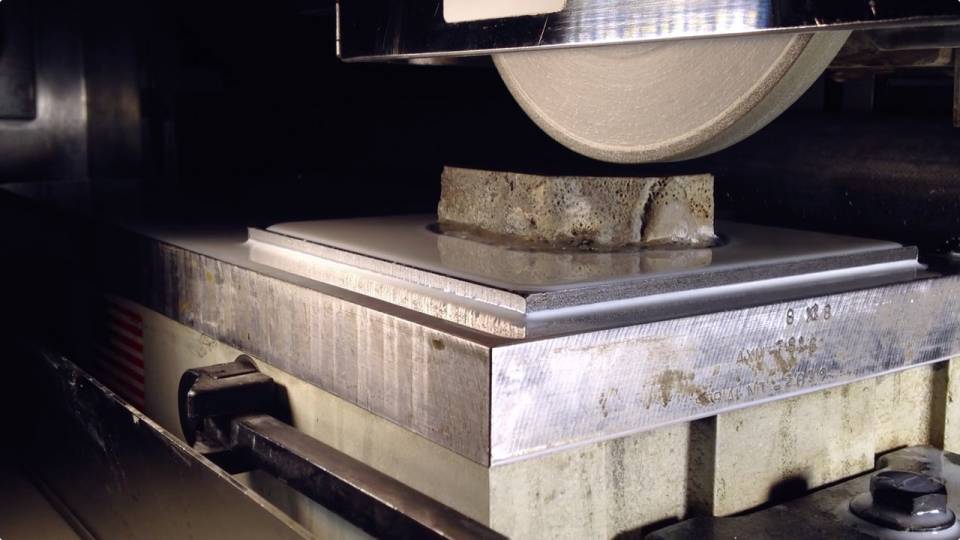 Laboratory grinder stripping layers of rock in a sample