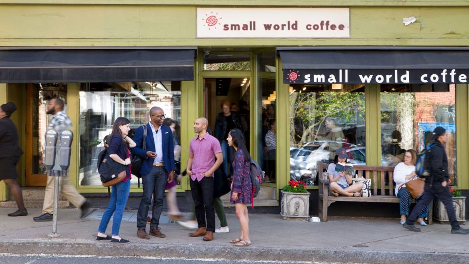 Frederick Wherry standing with students in front of coffee shop with people walking by