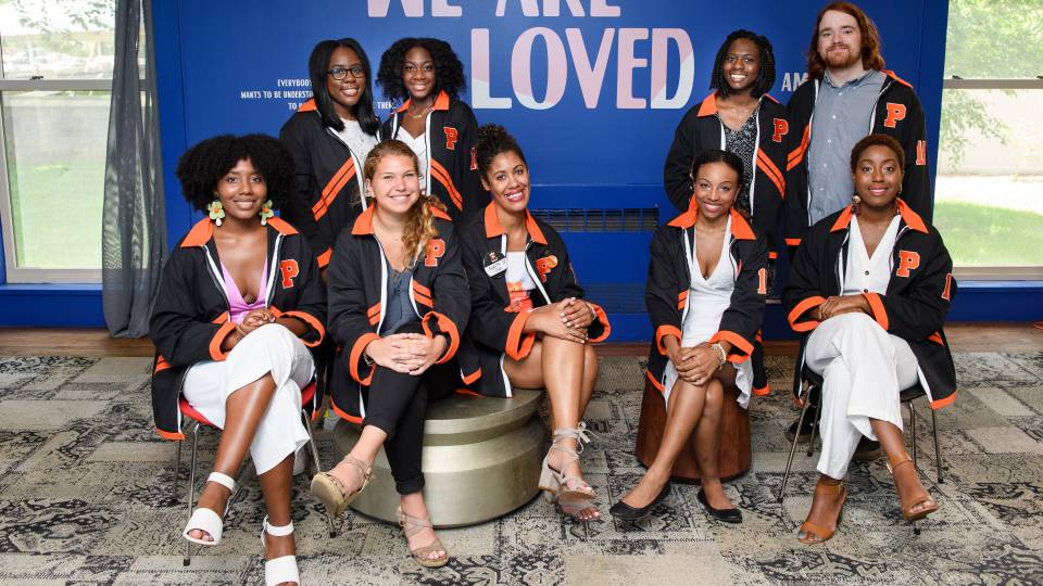Students sitting in front of wall that says "loved"