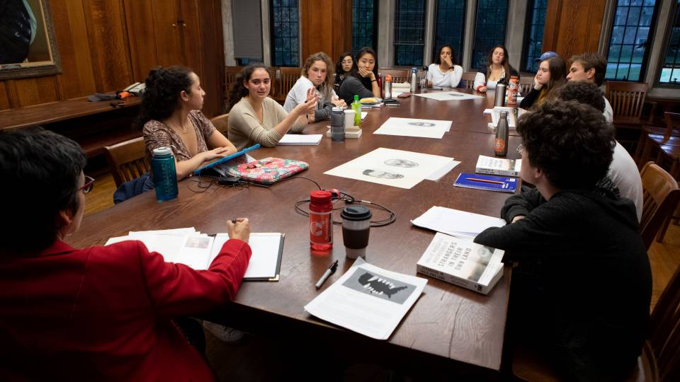 Students and professor sit around a atble