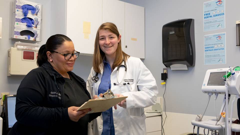 two women look at information on a clipboard