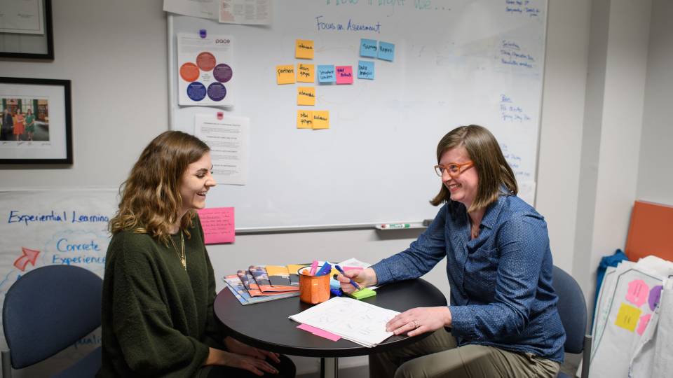 Eyestone and McNamara having a converation while sitting across a table from each other