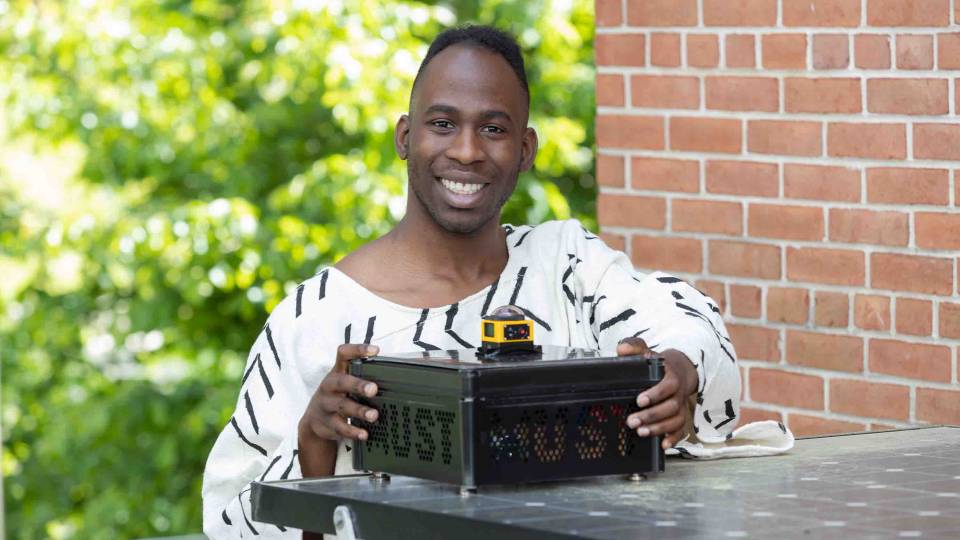 Jovan smiling with the device he used for his thesis