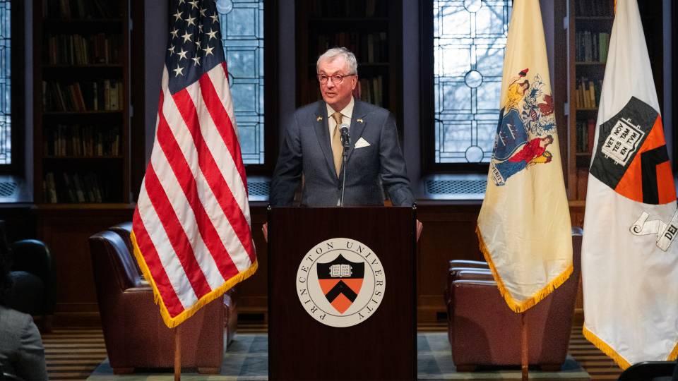 New Jersey Governor Phil Murphy standing in front of a podium in the Chancellor Green Library in front of a large audience