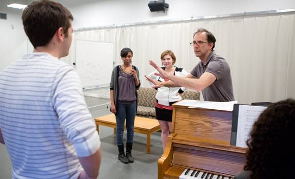 Students look on as John Rando holds up his hands