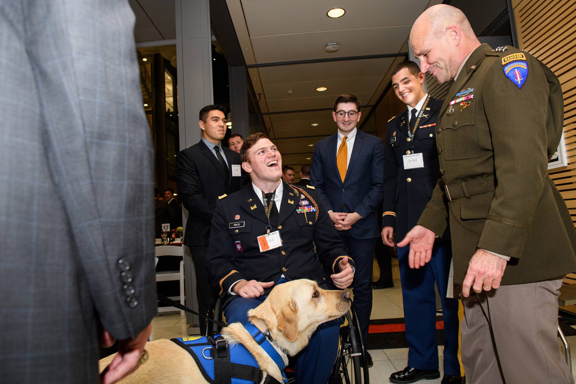 A group of people surround Victor Prato and his golden retriever