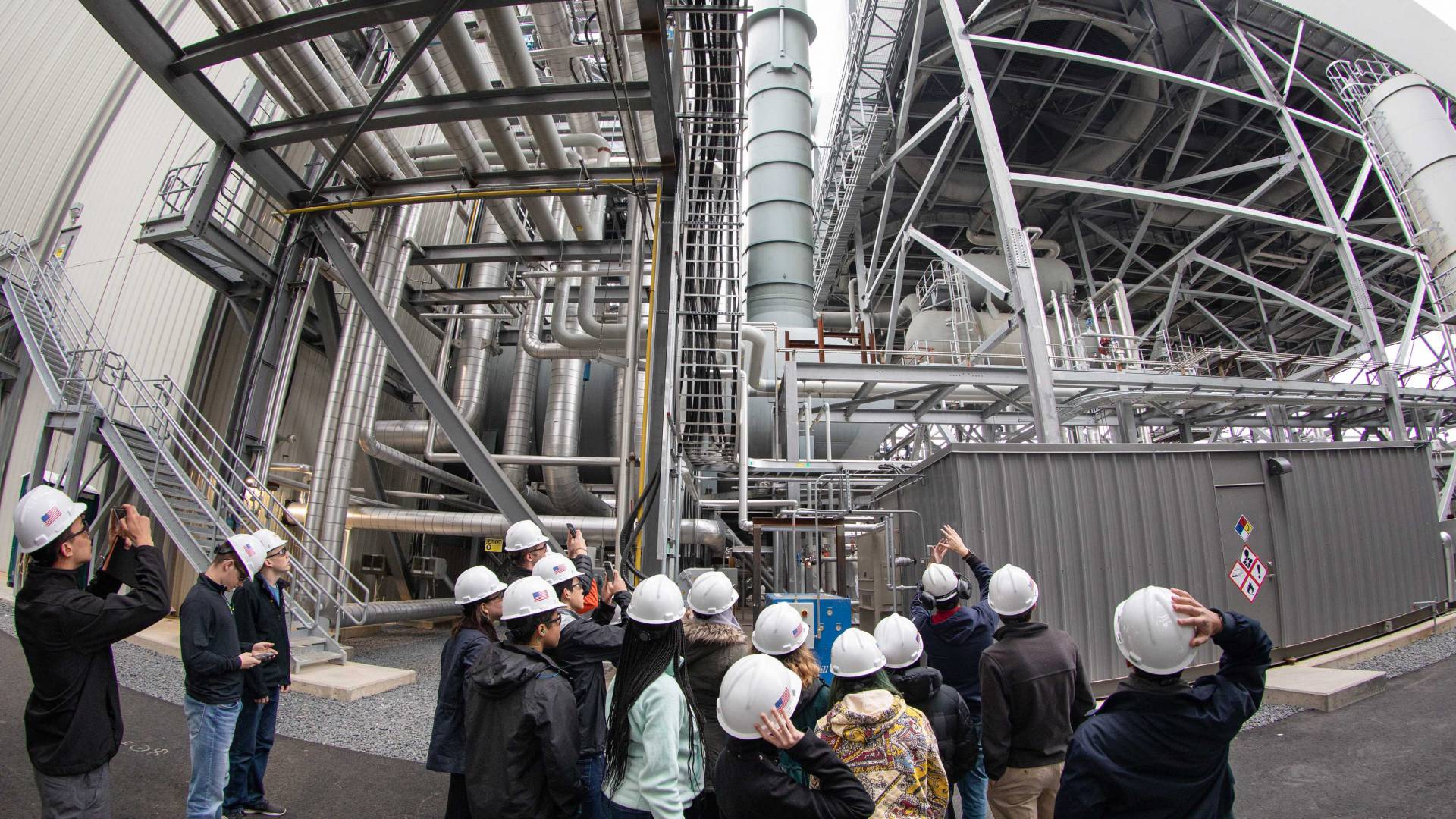 students in hard hats look at part of a power plant