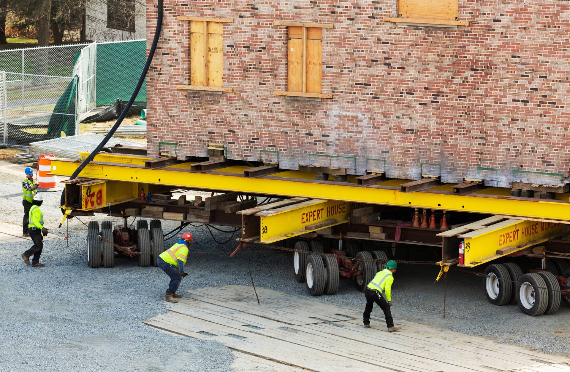 During the slow moving process, workmen check the positions of the wheels under the building