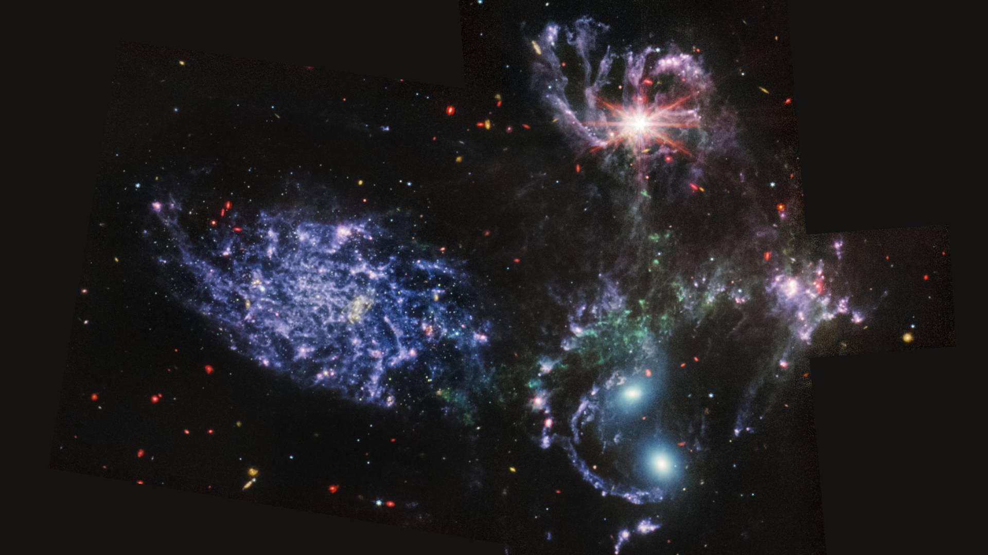 A group of five galaxies: The galaxy at the top has a bright reddish core surrounded by swirls of blue and purple. The galaxy on the left is a mass of purple gas surrounding a dim red core. 