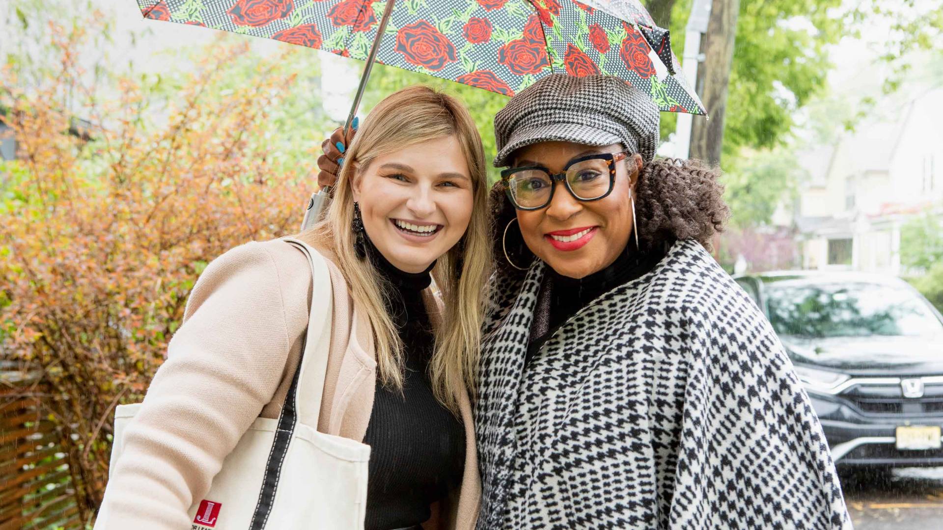 Two ladies smiling under an umbrella