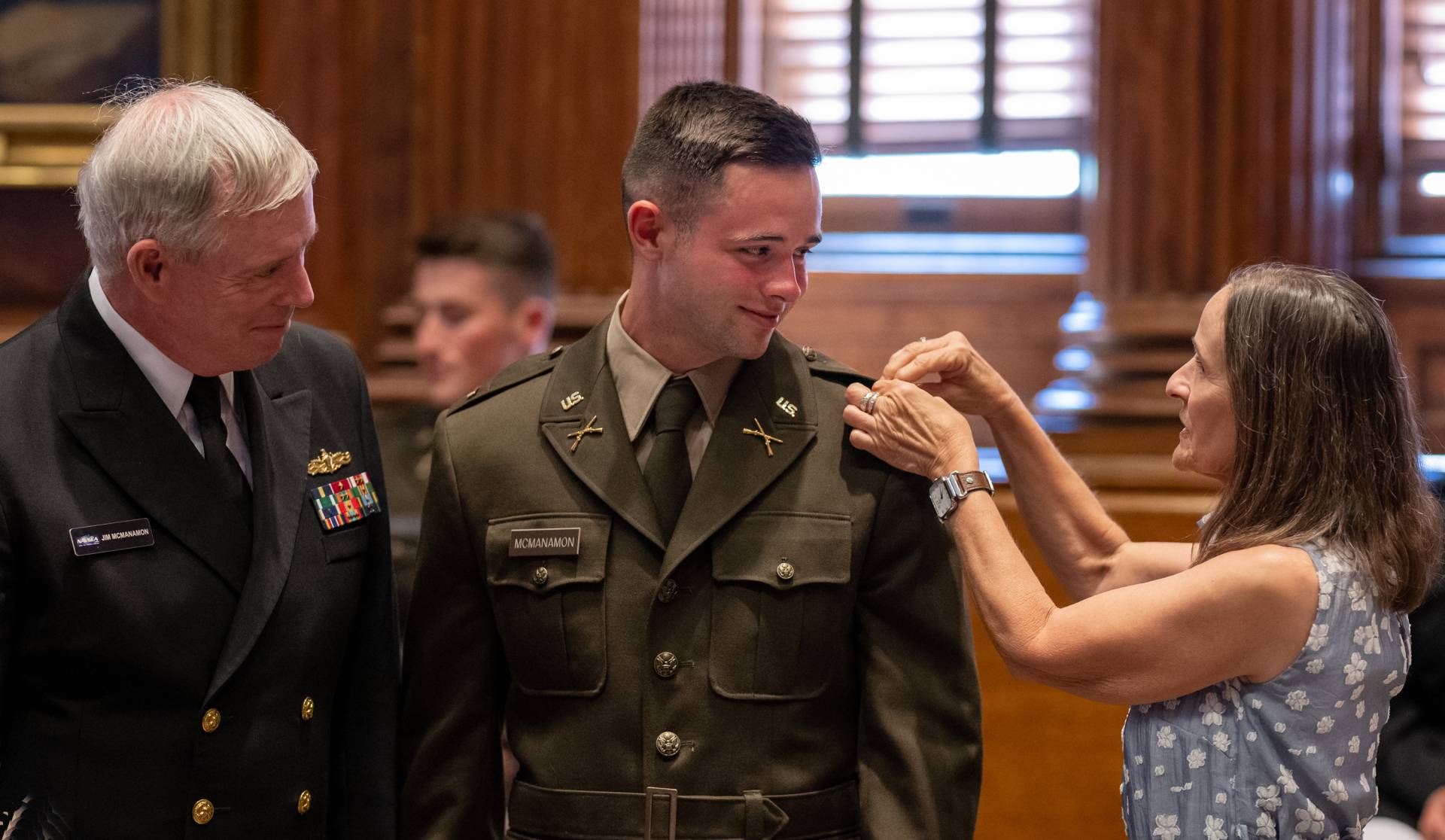 Parents pin the bars on their son's shoulders