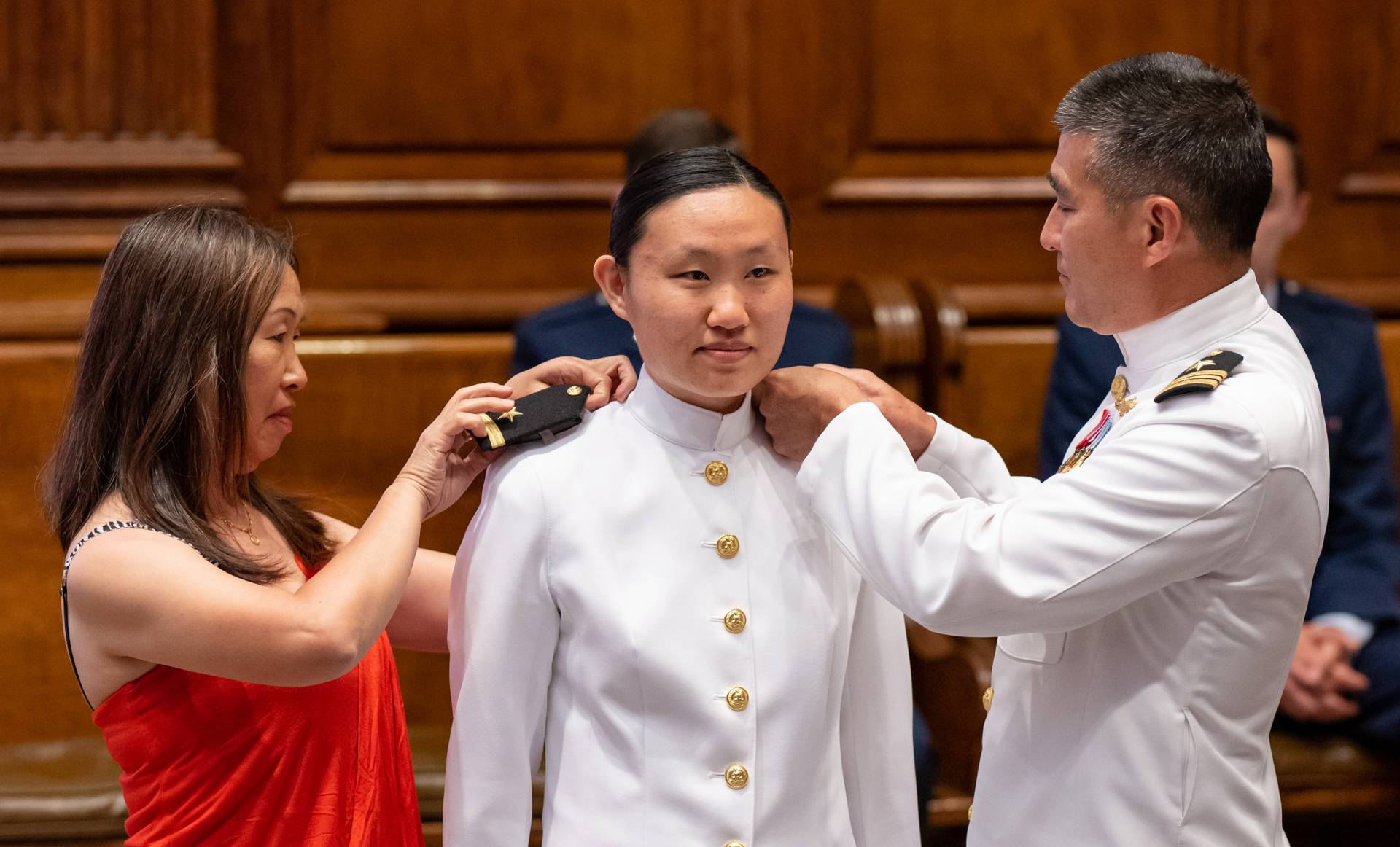 Parents pin bars on their daughter's shoulders