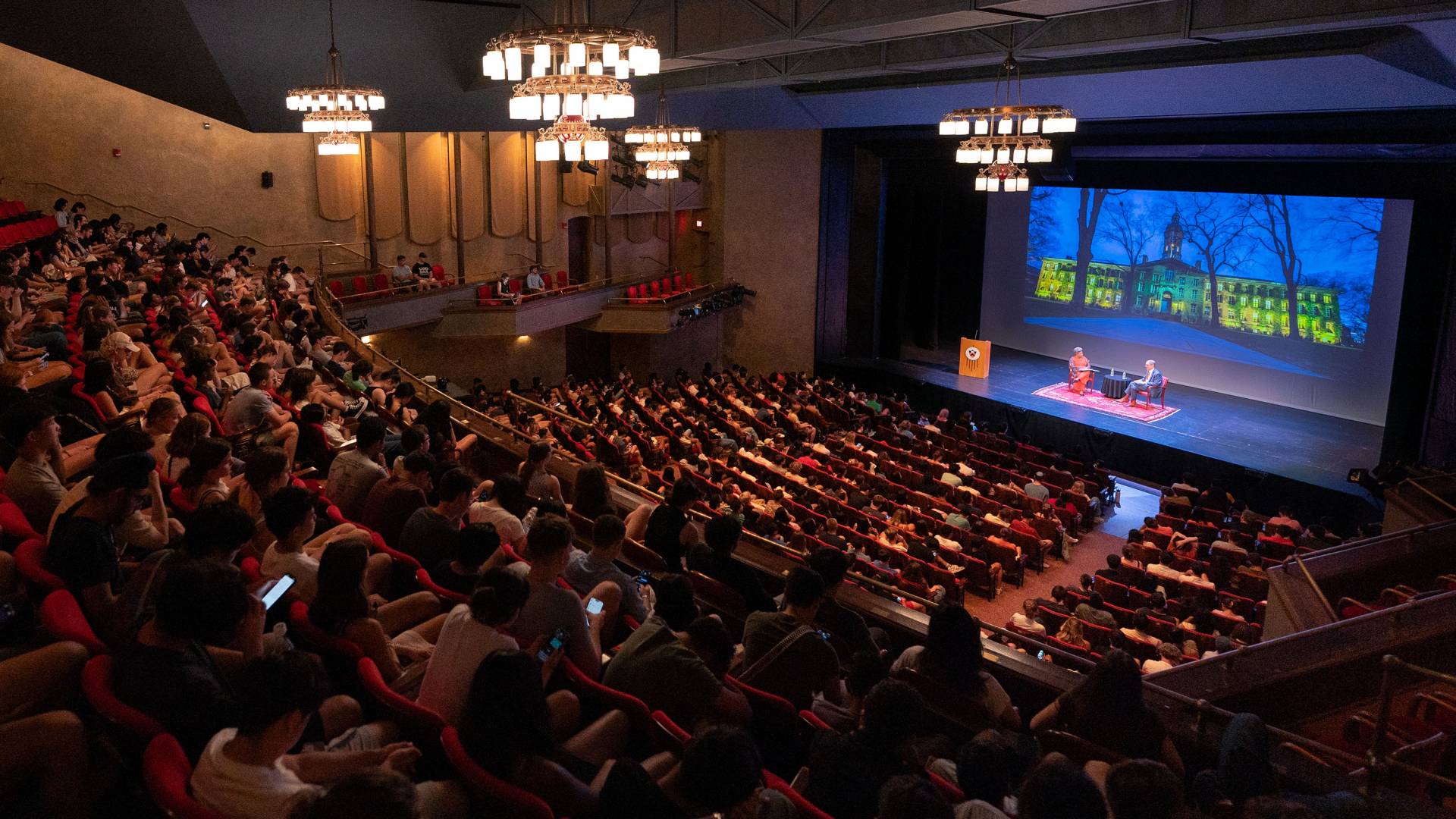 A full theatre of students watching President Eisgruber and Rochelle Calhoun speaking on stage