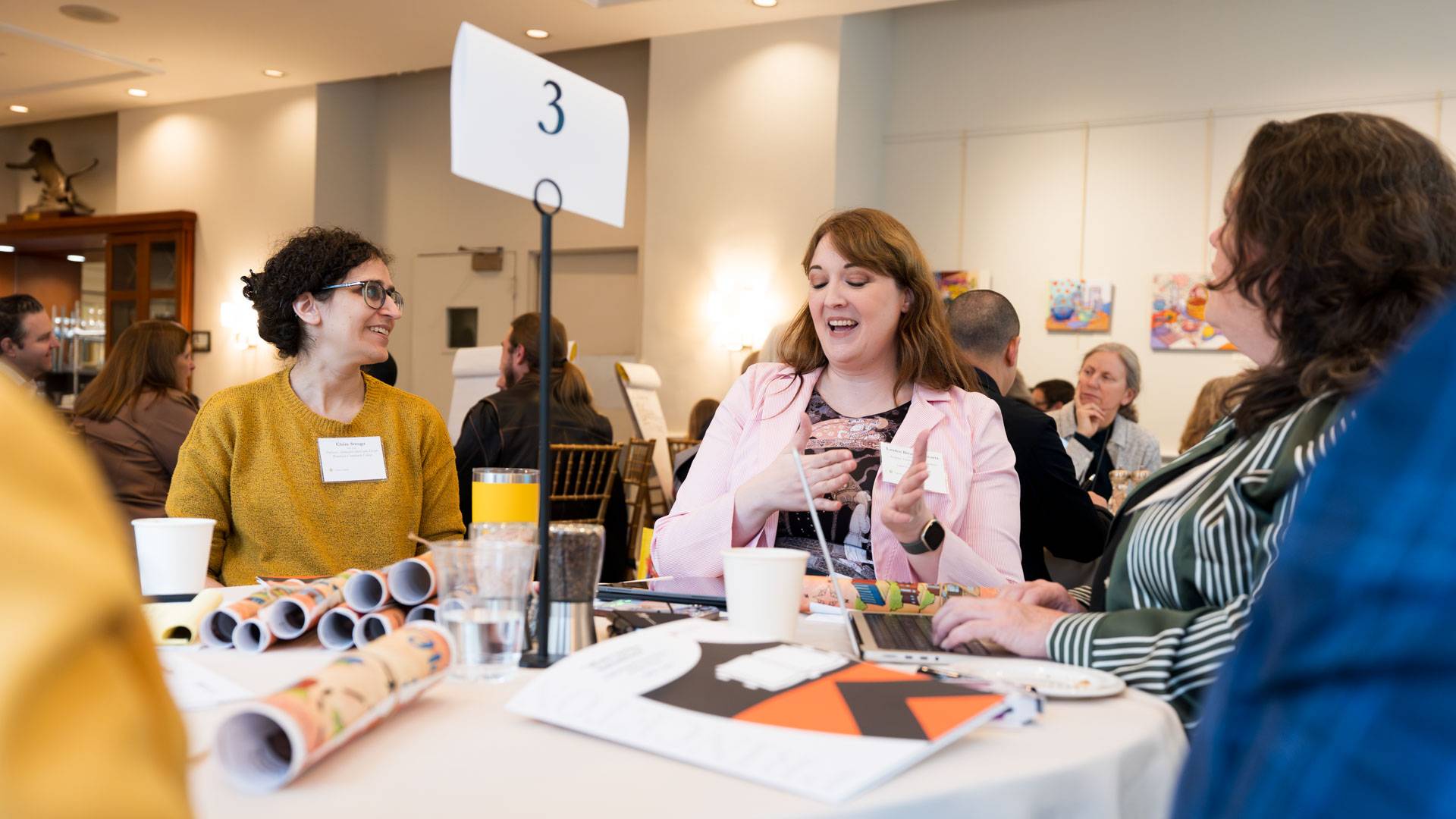 Three women talk at a table.