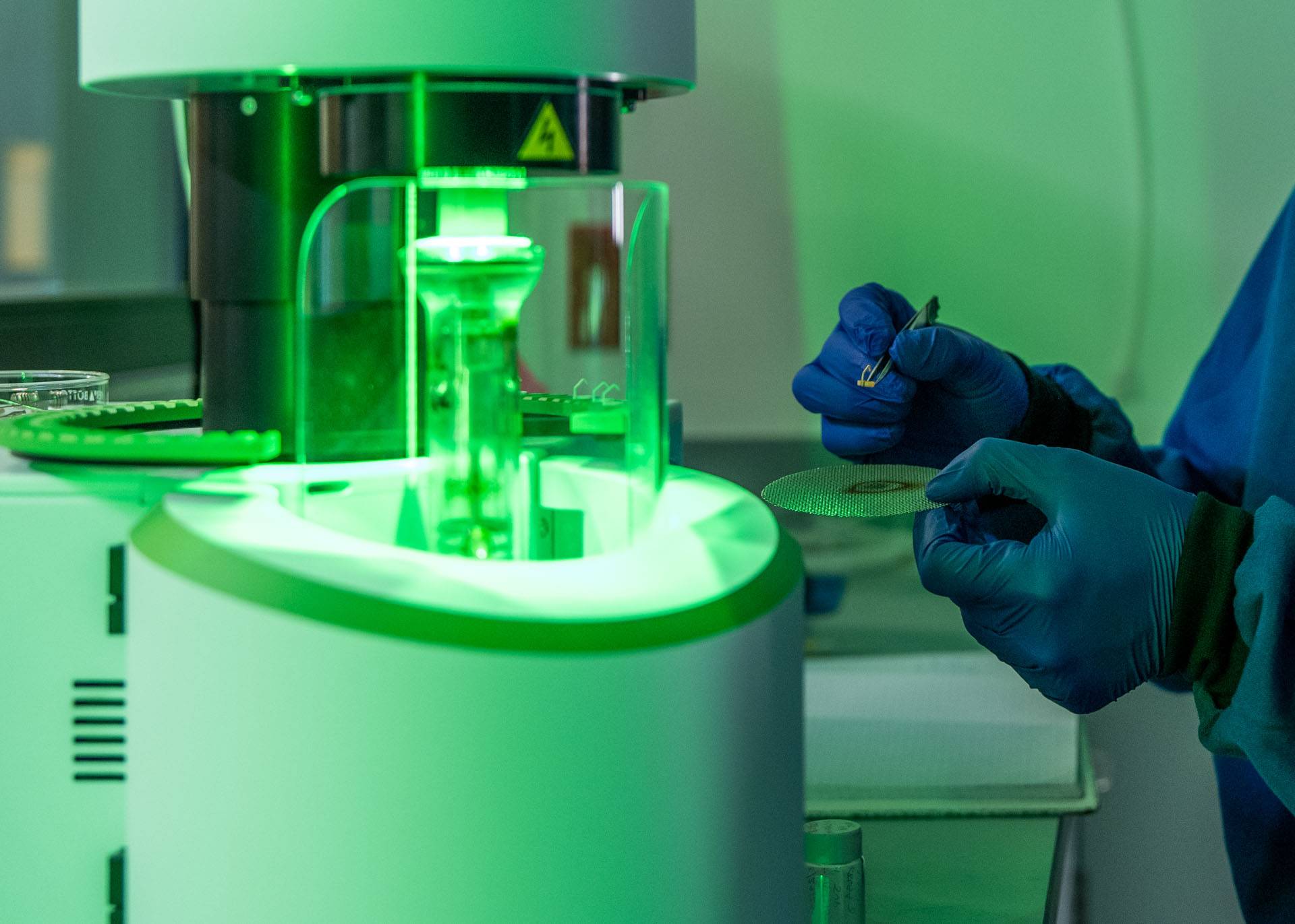 A person inside a lab wearing latex gloves holding lab equipments
