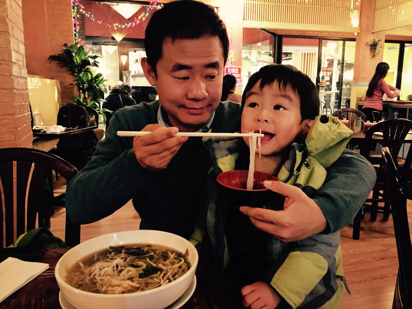 Wang enjoys a meal of noodles with his young son.