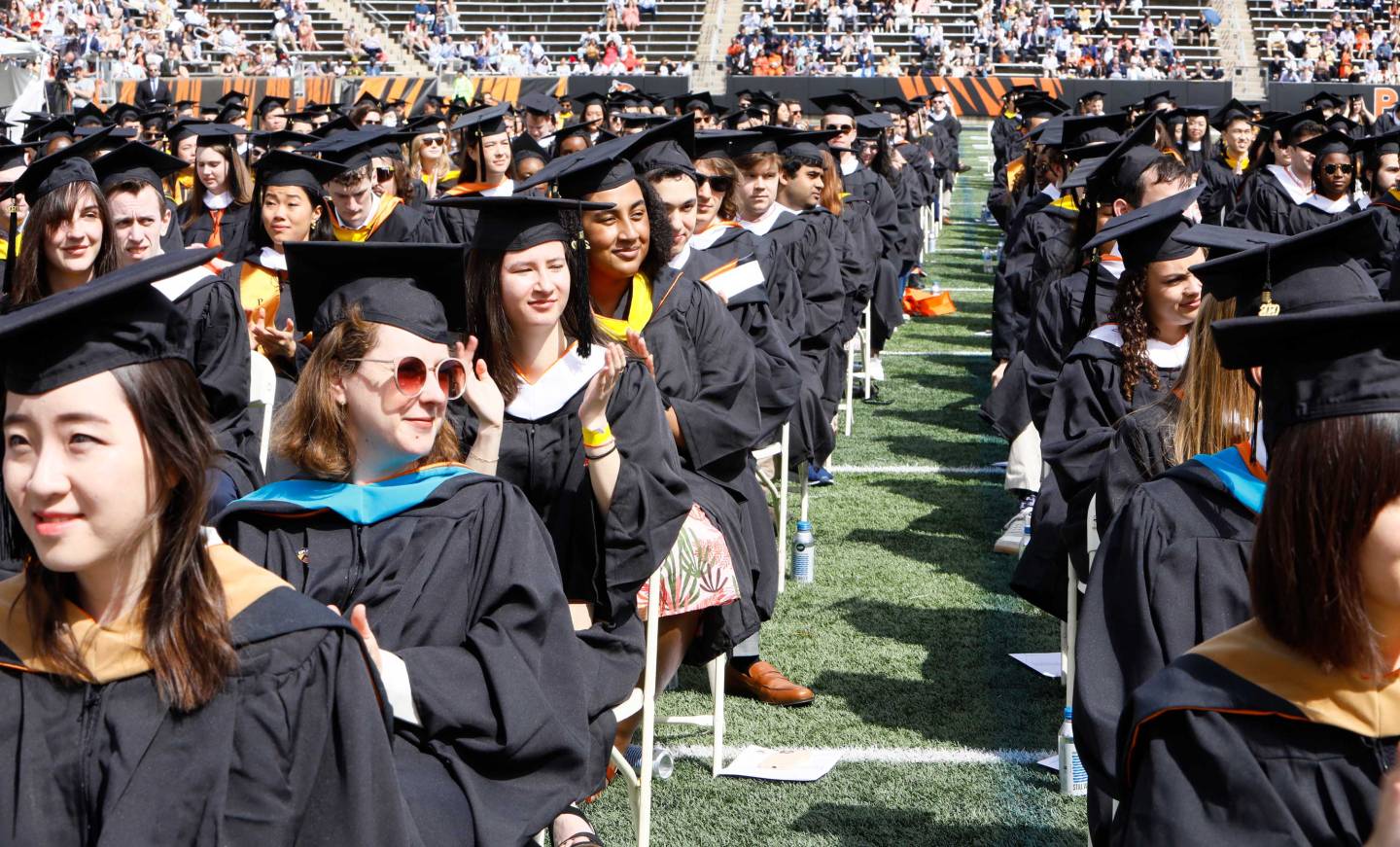 Graduate alumni sit in the stadium