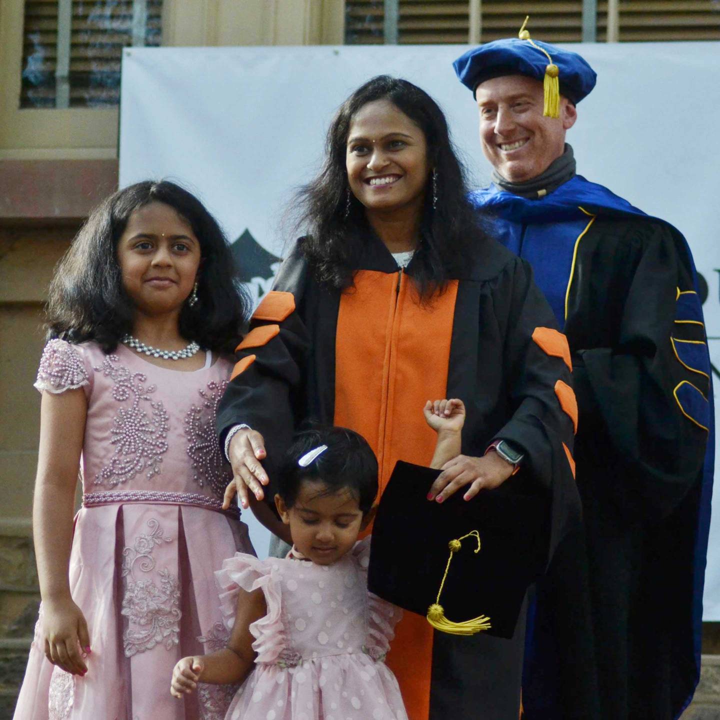 A family on stage receiving their mother's graduate hood