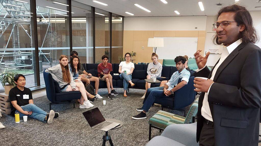 A man points as he speaks to students