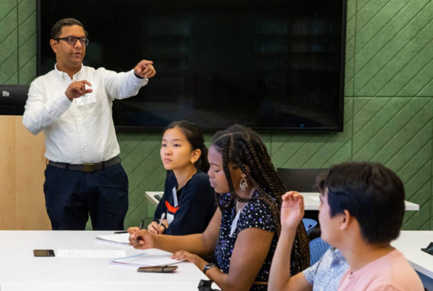 A man points as he speaks to students